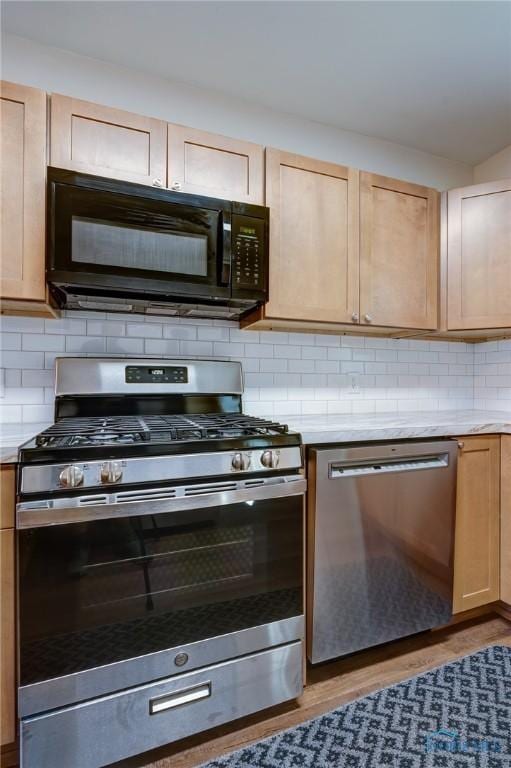 kitchen featuring light brown cabinetry, appliances with stainless steel finishes, light hardwood / wood-style flooring, and tasteful backsplash