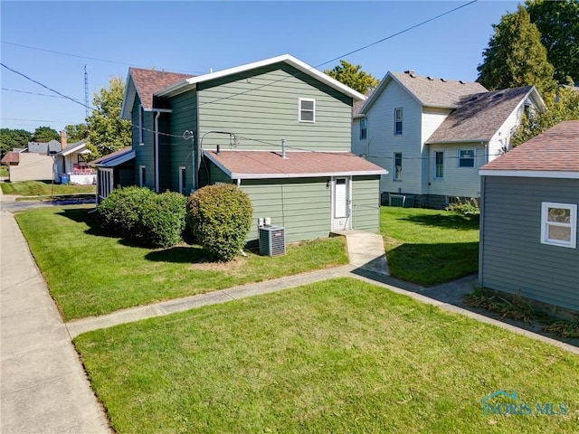 rear view of property featuring a yard and central AC unit