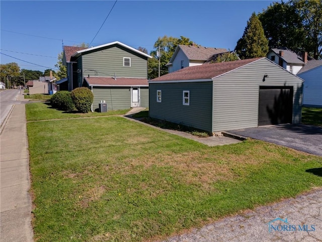 view of side of home featuring a garage, cooling unit, an outdoor structure, and a lawn