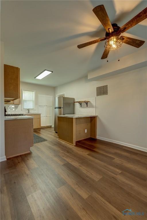 kitchen featuring kitchen peninsula, dark wood-type flooring, ceiling fan, and stainless steel fridge