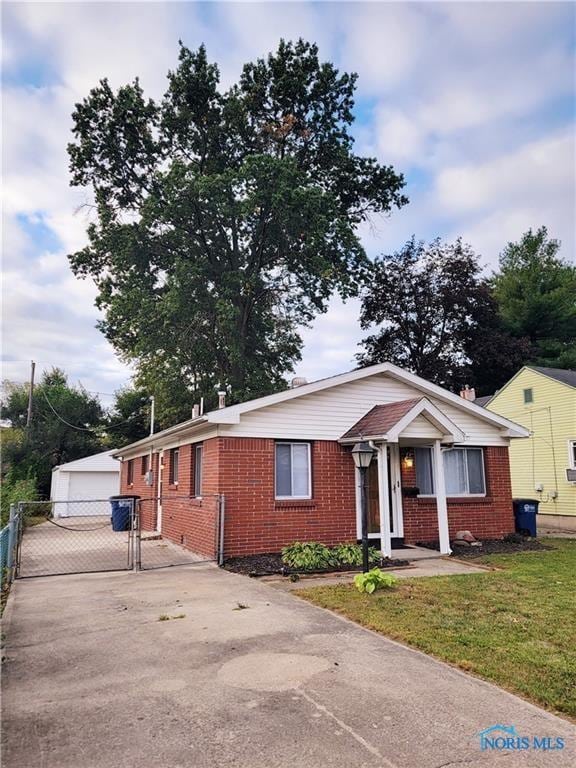 view of front of property featuring a front yard, a garage, and an outbuilding