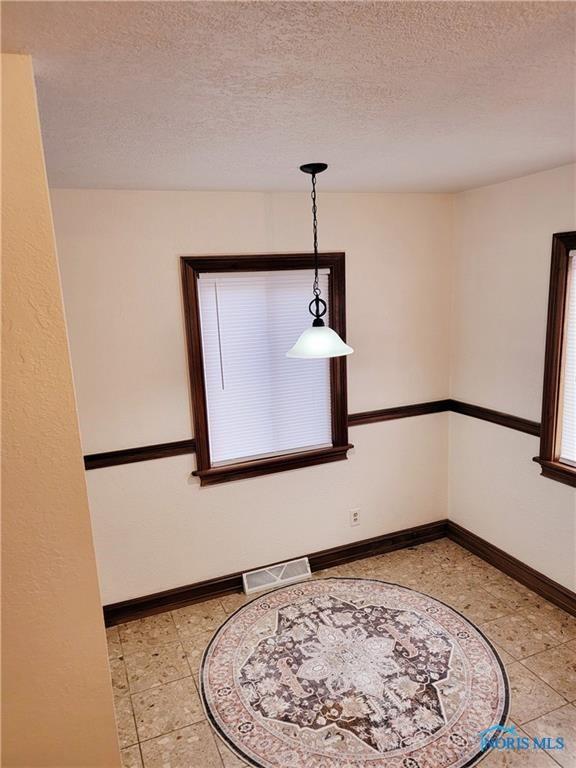 unfurnished dining area featuring a textured ceiling