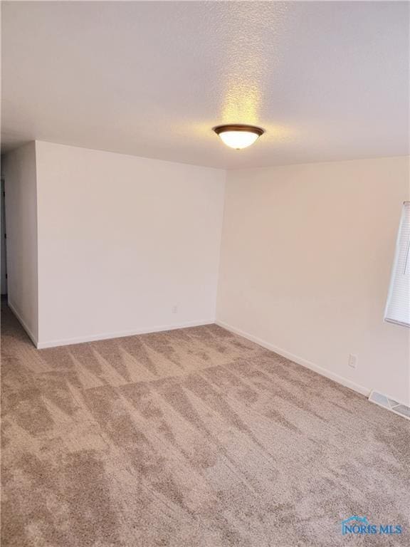 spare room featuring a textured ceiling and carpet flooring