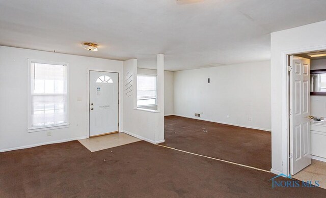 entrance foyer with dark carpet and baseboards