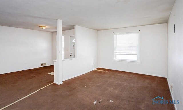 spare room with visible vents, dark carpet, and baseboards