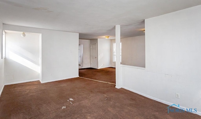 unfurnished room with dark colored carpet and baseboards