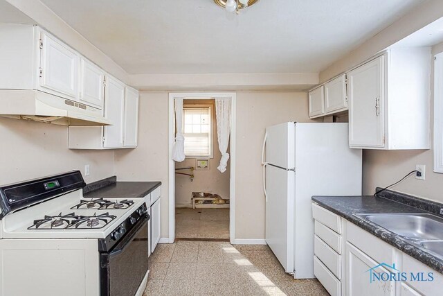 kitchen featuring under cabinet range hood, white appliances, white cabinetry, baseboards, and dark countertops