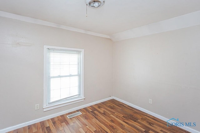 empty room with baseboards, visible vents, and dark wood-style flooring