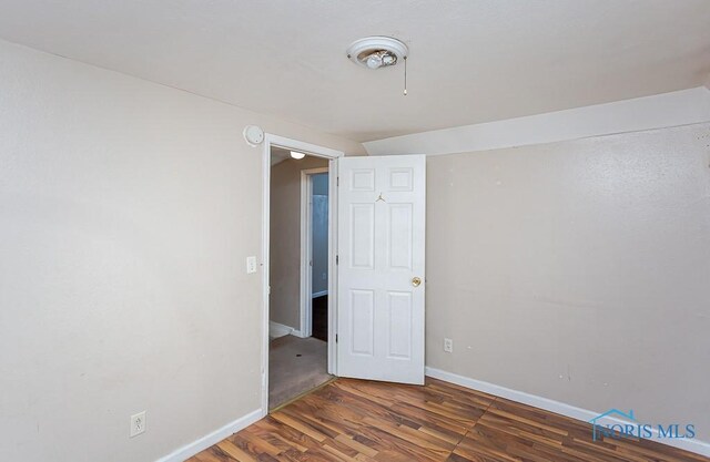 unfurnished room featuring baseboards and dark wood finished floors