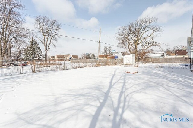 snowy yard with a residential view and fence