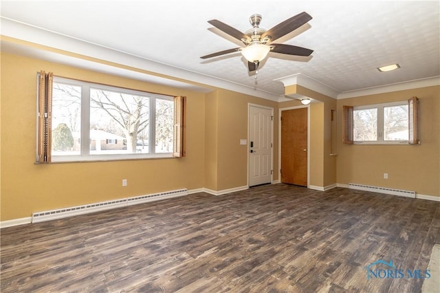 empty room with dark wood-type flooring, a baseboard radiator, and a wealth of natural light