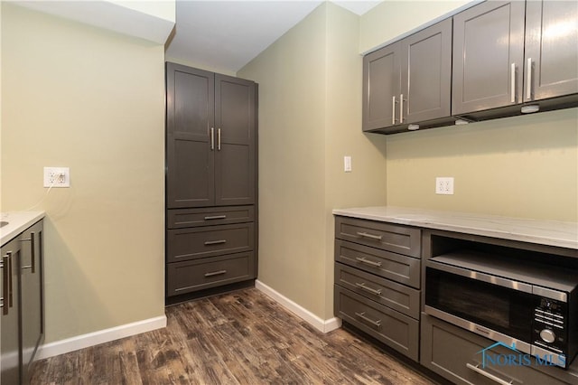 kitchen with light stone counters, dark wood-type flooring, and gray cabinets