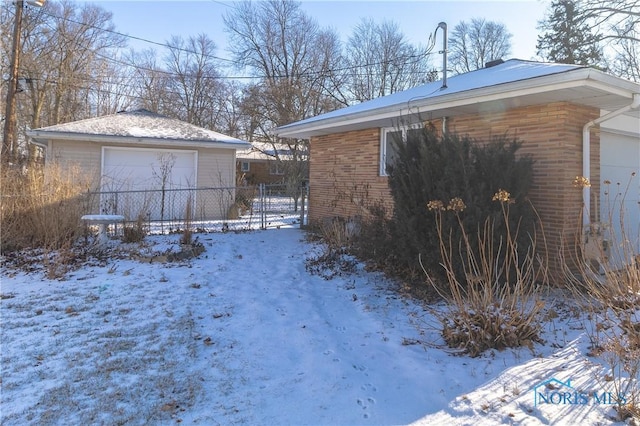 view of snow covered exterior featuring a garage and an outdoor structure