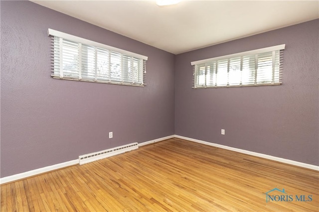 spare room featuring a baseboard radiator and wood-type flooring