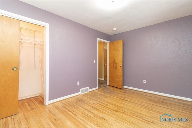 unfurnished bedroom featuring light hardwood / wood-style flooring and a closet