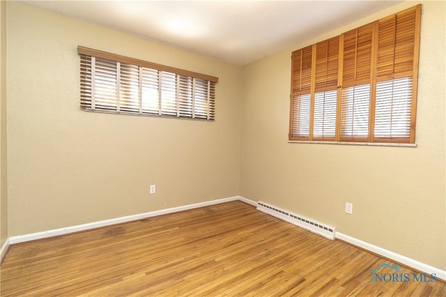 unfurnished room with hardwood / wood-style floors and baseboard heating