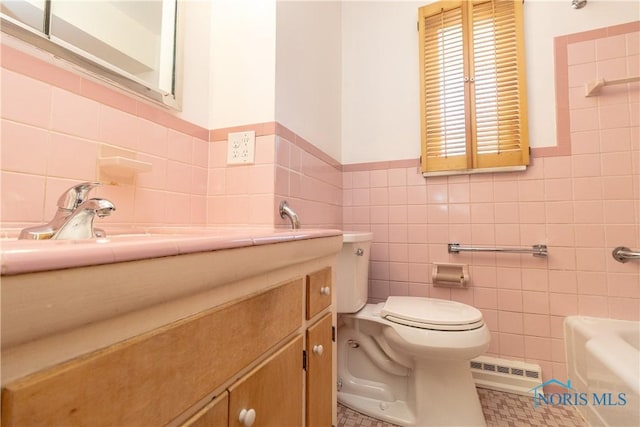 bathroom with tile patterned floors, toilet, tile walls, vanity, and a bathtub