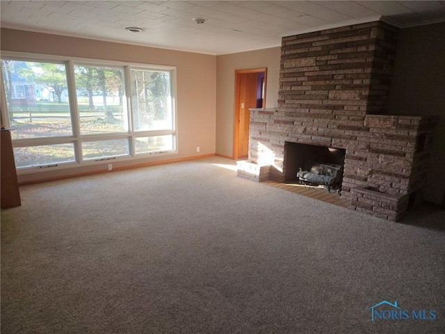 unfurnished living room featuring crown molding, a stone fireplace, a healthy amount of sunlight, and carpet