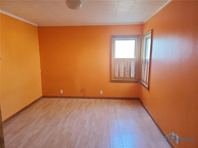 empty room with ornamental molding and light wood-type flooring