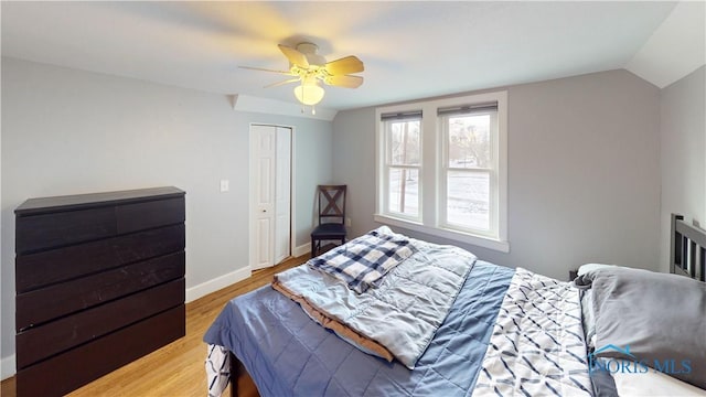 bedroom with ceiling fan, vaulted ceiling, a closet, and light hardwood / wood-style flooring