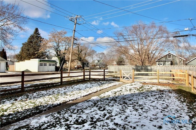 yard layered in snow featuring a garage and an outbuilding