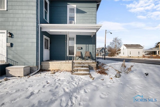 snow covered property entrance featuring covered porch