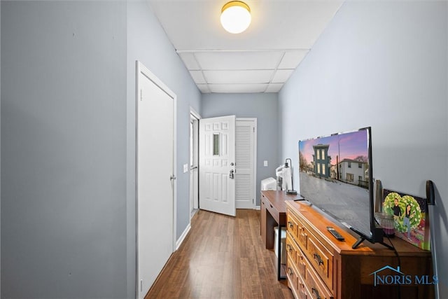 hallway with dark wood-type flooring and a drop ceiling