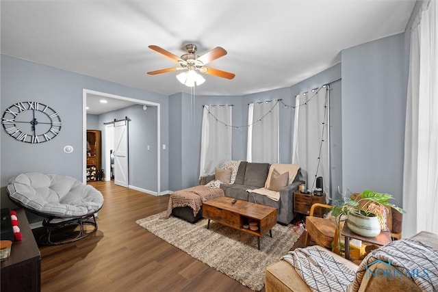 living room with hardwood / wood-style floors, a barn door, and ceiling fan