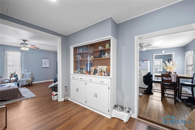 interior space featuring white refrigerator, ceiling fan, wood-type flooring, and crown molding