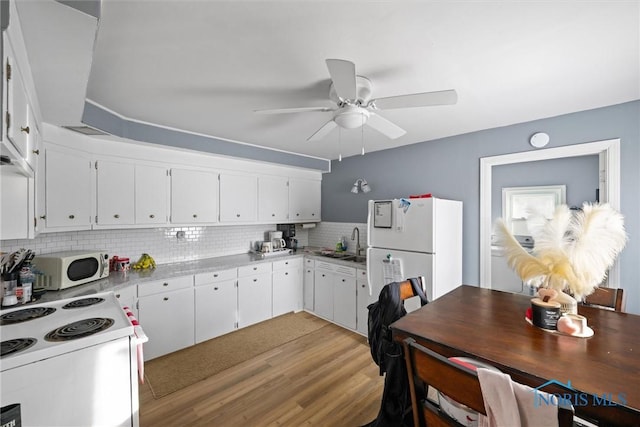 kitchen featuring sink, white appliances, light hardwood / wood-style flooring, white cabinets, and decorative backsplash