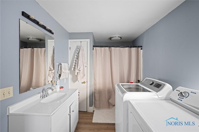 laundry area with washing machine and clothes dryer, wood-type flooring, and sink