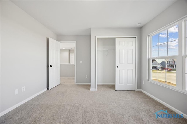 unfurnished bedroom with light colored carpet and a closet