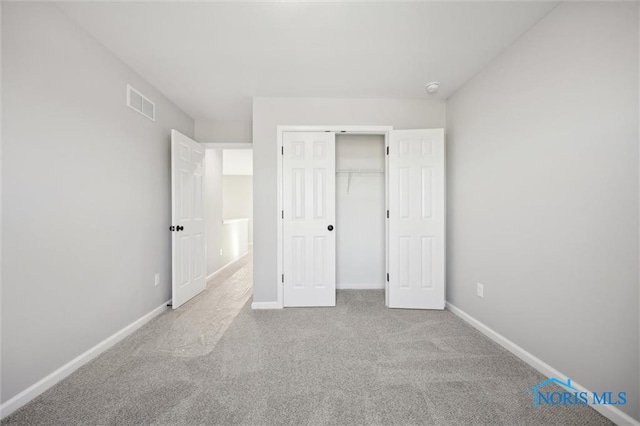 unfurnished bedroom featuring light colored carpet and a closet