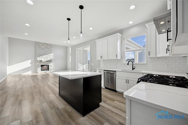 kitchen featuring white cabinets, stainless steel dishwasher, a kitchen island, and a fireplace