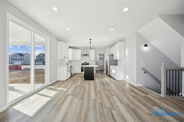 kitchen featuring white cabinets, pendant lighting, appliances with stainless steel finishes, and a kitchen island