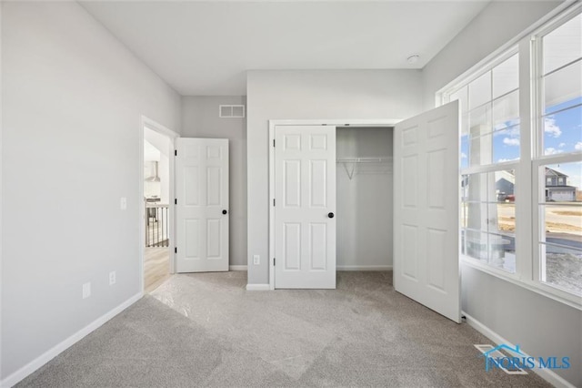 unfurnished bedroom with light colored carpet, a closet, and multiple windows