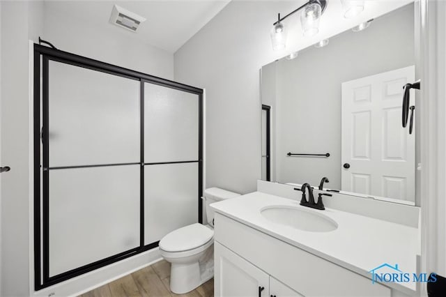 bathroom with toilet, an enclosed shower, vanity, and hardwood / wood-style flooring