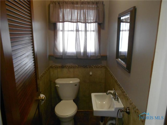 bathroom with sink, tile walls, and toilet