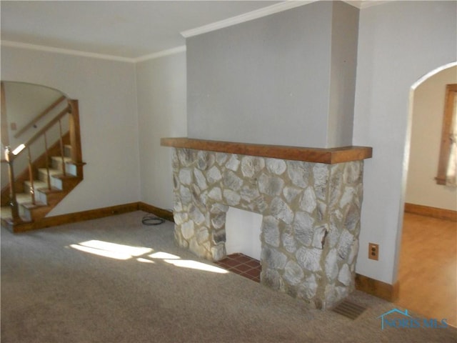 carpeted living room with ornamental molding and a stone fireplace