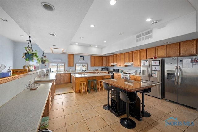 kitchen featuring stainless steel refrigerator with ice dispenser, a breakfast bar, a kitchen island, and white range oven