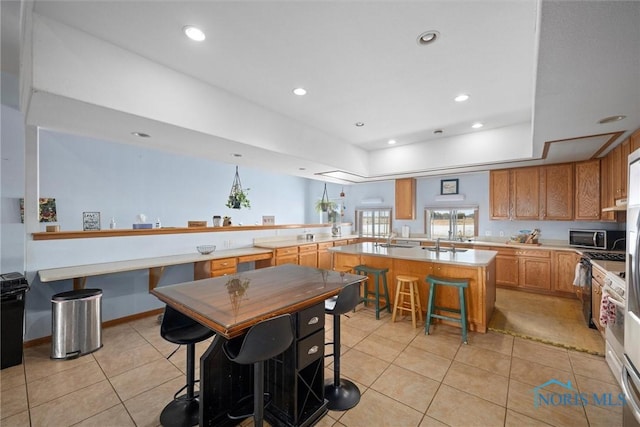 kitchen featuring light tile patterned flooring, sink, a kitchen bar, a center island, and kitchen peninsula