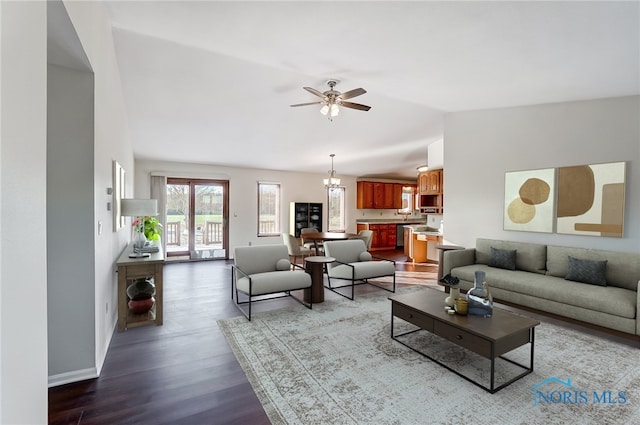 living room with ceiling fan with notable chandelier, hardwood / wood-style floors, and vaulted ceiling