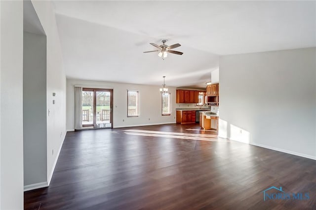 unfurnished living room featuring ceiling fan with notable chandelier, vaulted ceiling, and dark hardwood / wood-style flooring