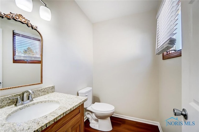 bathroom with toilet, vanity, and hardwood / wood-style flooring