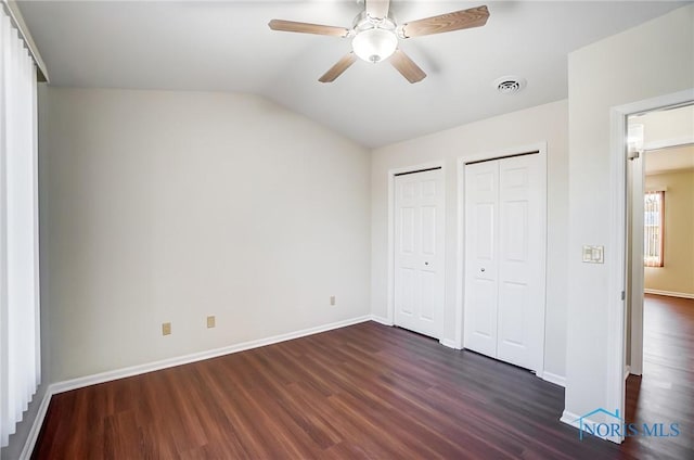 unfurnished bedroom with vaulted ceiling, multiple closets, ceiling fan, and dark hardwood / wood-style floors