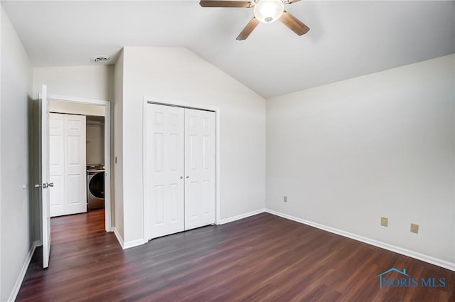 unfurnished bedroom with washer / clothes dryer, vaulted ceiling, a closet, ceiling fan, and dark hardwood / wood-style floors