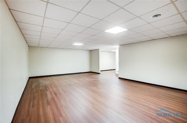 unfurnished room with hardwood / wood-style flooring and a drop ceiling