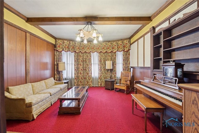 sitting room with a notable chandelier, beamed ceiling, and carpet