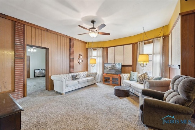 carpeted living room featuring wooden walls and ceiling fan