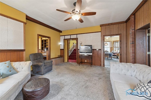 living room featuring carpet flooring, ceiling fan, and wood walls